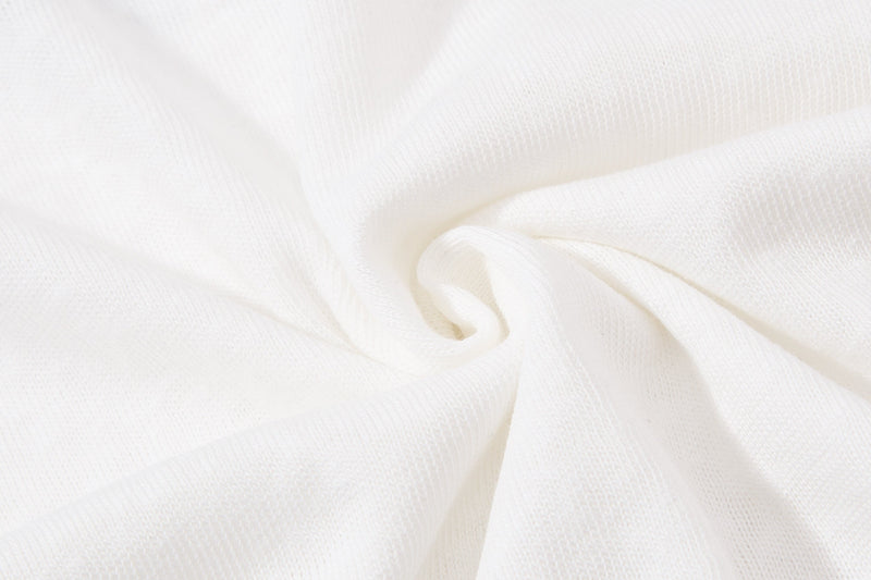 Close-up of white textured fabric with soft folds, showing the material of a men's vintage streetwear graphic polo shirt