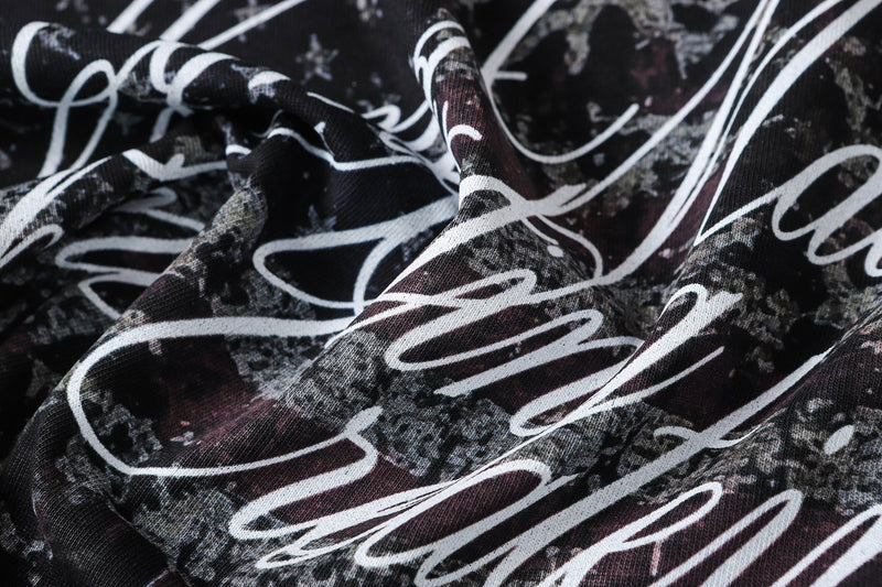 Close-up of the camo-and-script printed fabric with white lettering on black background