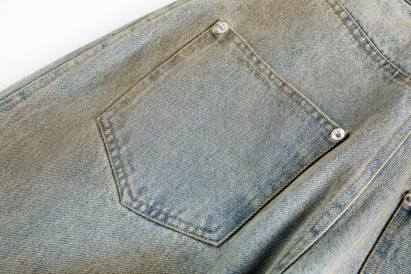 Close-up of back pocket on light blue washed denim jeans with silver rivets