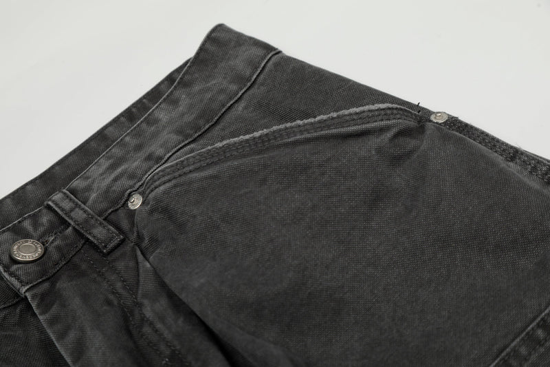 Close-up of the front pocket and waistband seam on washed black cargo denim pants