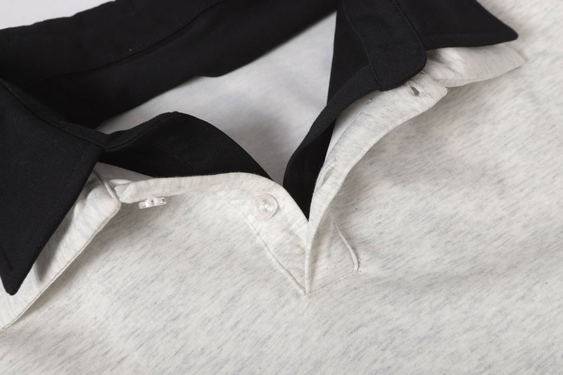 Close-up of layered polo neckline with black collar and light gray fabric, showing button placket detail