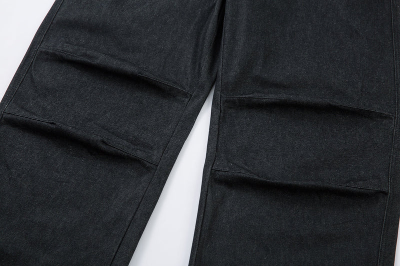 Close-up of both wide pant legs with horizontal pleat seams near the lower thighs