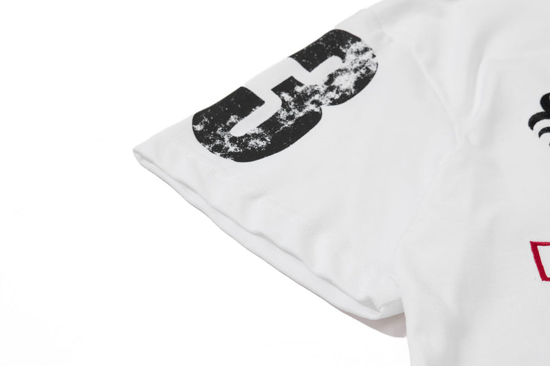 White streetwear polo tee with a bold distressed black graphic on the sleeve and chest detail