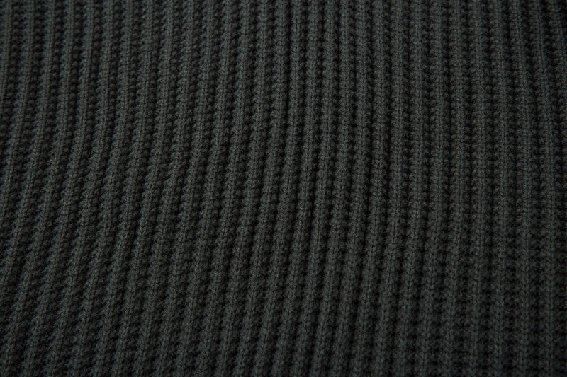 Close-up of dark ribbed knit sweater body with vertical rib texture