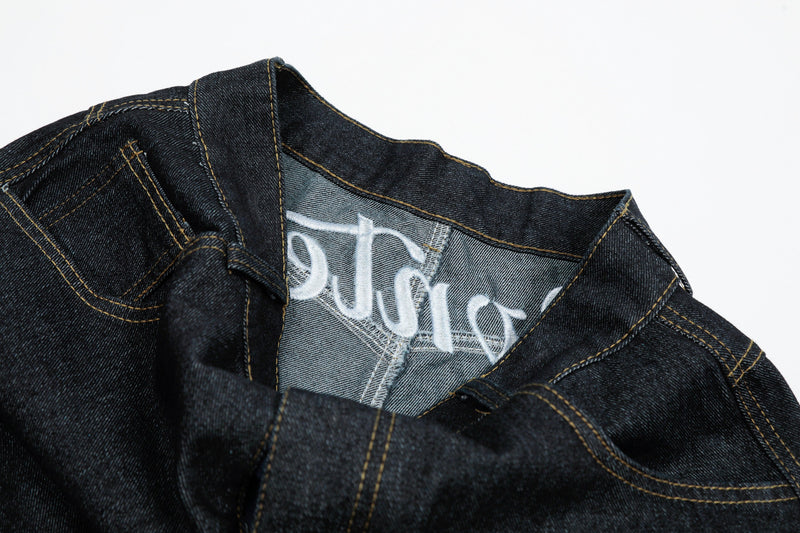 Inner waistband close-up of black denim jeans with white embroidered script on the lining
