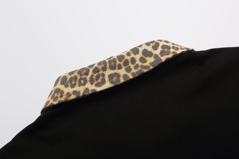 Black polo shirt with a leopard print collar, shown in a close-up on a clean white background