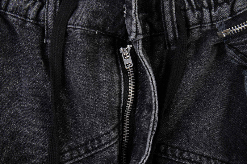 Close-up of black denim zipper fly with drawstrings and plaid layers