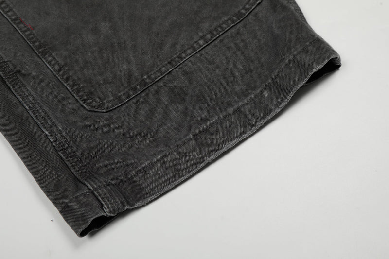 Close-up of the wide hem on washed black denim cargo pants