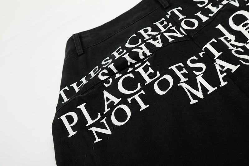 Close-up of white lettering print on black cargo pants at the back waist seam