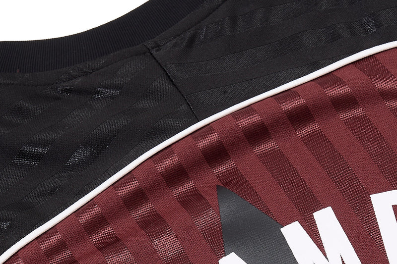Close-up of a black and burgundy striped football jersey tee with textured fabric and white piping detail
