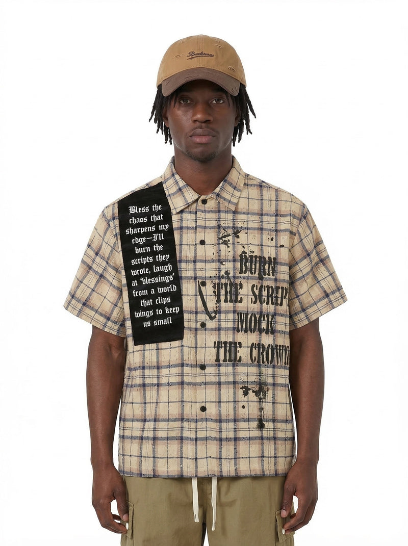 Beige plaid short-sleeve streetwear shirt with black graphic script and distressed details on a model