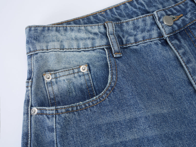Close-up of front pocket, belt loop, and rivets on light washed blue jeans