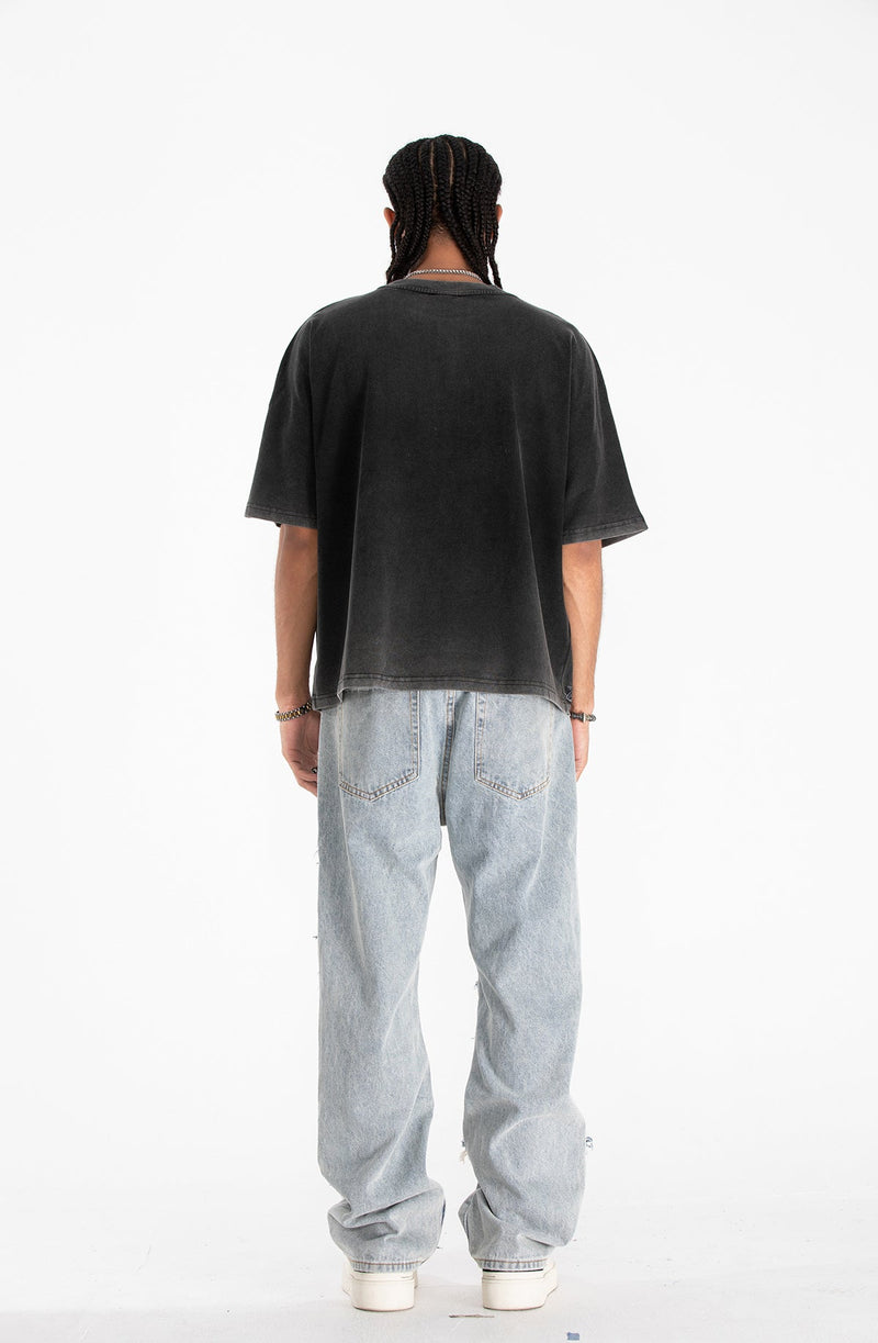 Back view of black oversized gothic graphic tee styled with loose light wash jeans and white sneakers