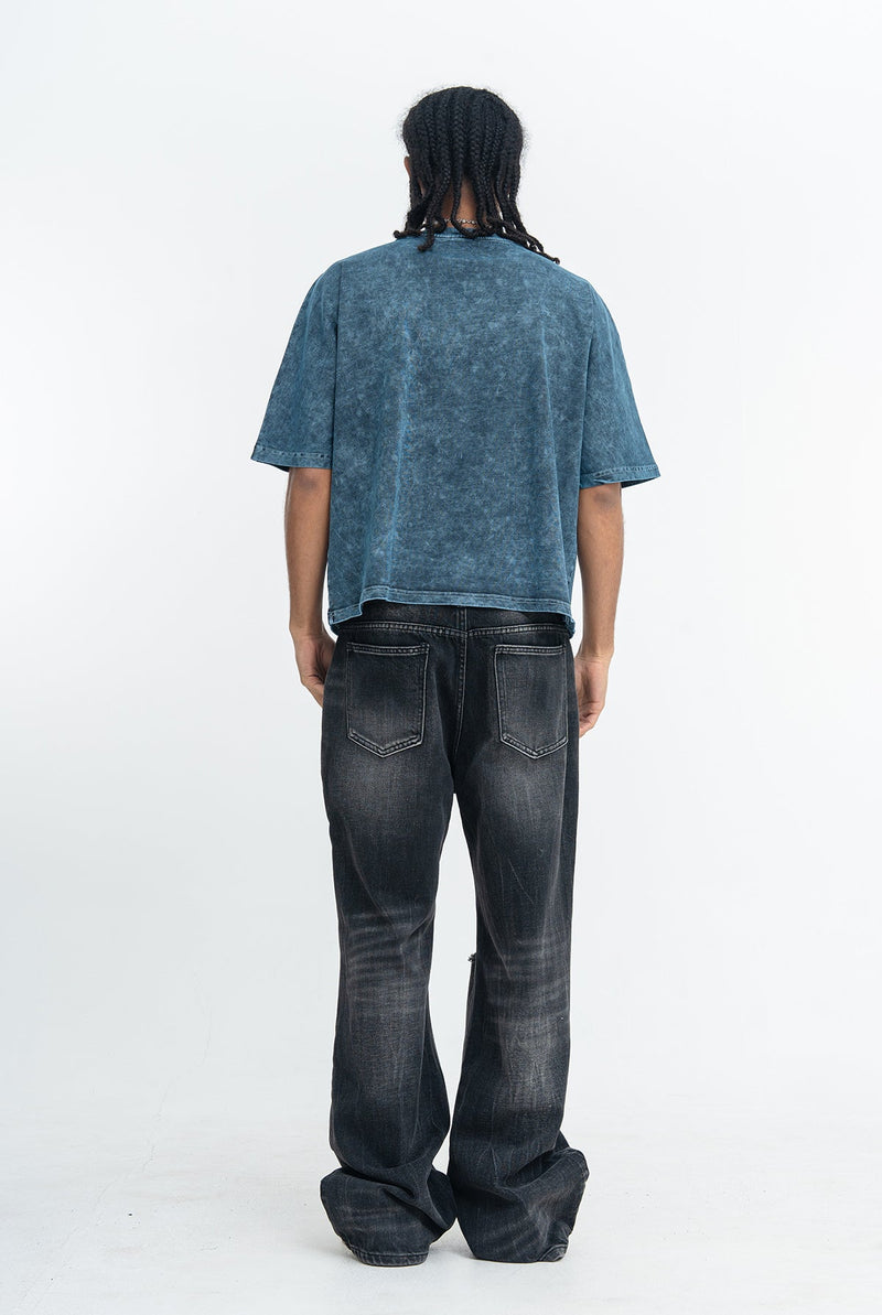 Back view of a model wearing a vintage washed blue oversized gothic graphic T-shirt with dark baggy jeans