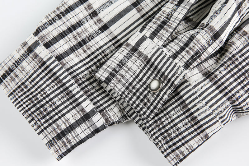 Close-up of plaid sleeve cuffs with buttoned tab detail on the sweater