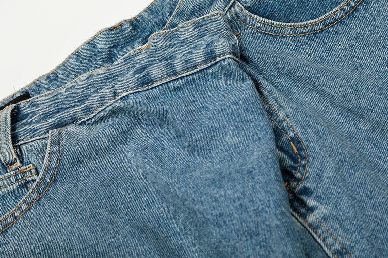 Close-up of asymmetric waistband and front seam on blue denim jeans
