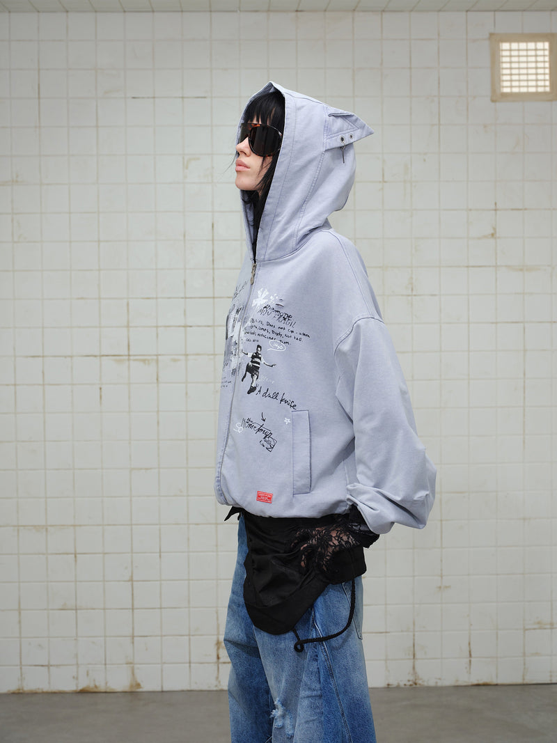 Side view of model in gray graphic zip hoodie with hood up and sunglasses