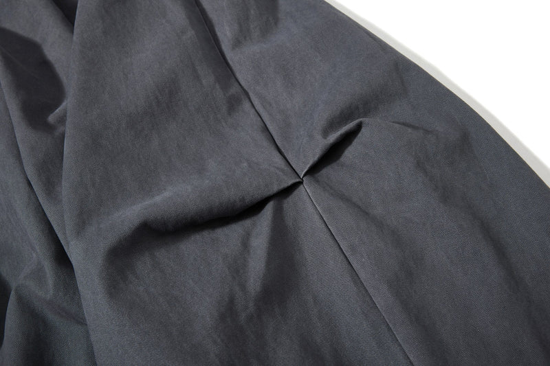 Close-up of dark gray pant leg with smooth drape and wide cut