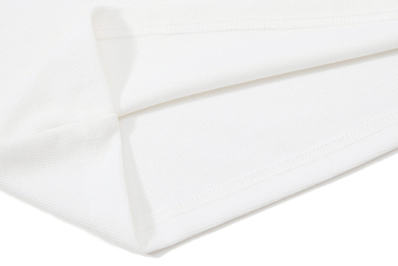 Close-up of white textured polo shirt fabric with folded hem and contrast collar detail