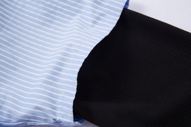 Close-up of blue pinstripe shirt fabric layered over black textured sleeve