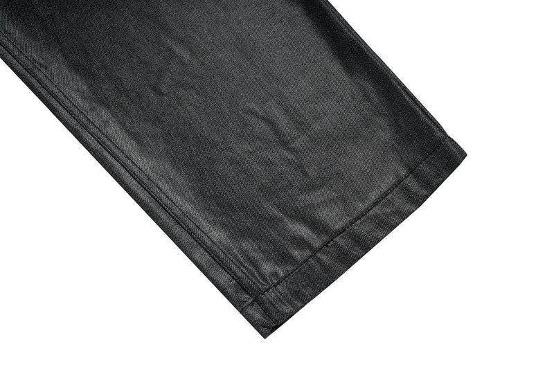 Black wide-leg denim pant hem with coated finish, close-up