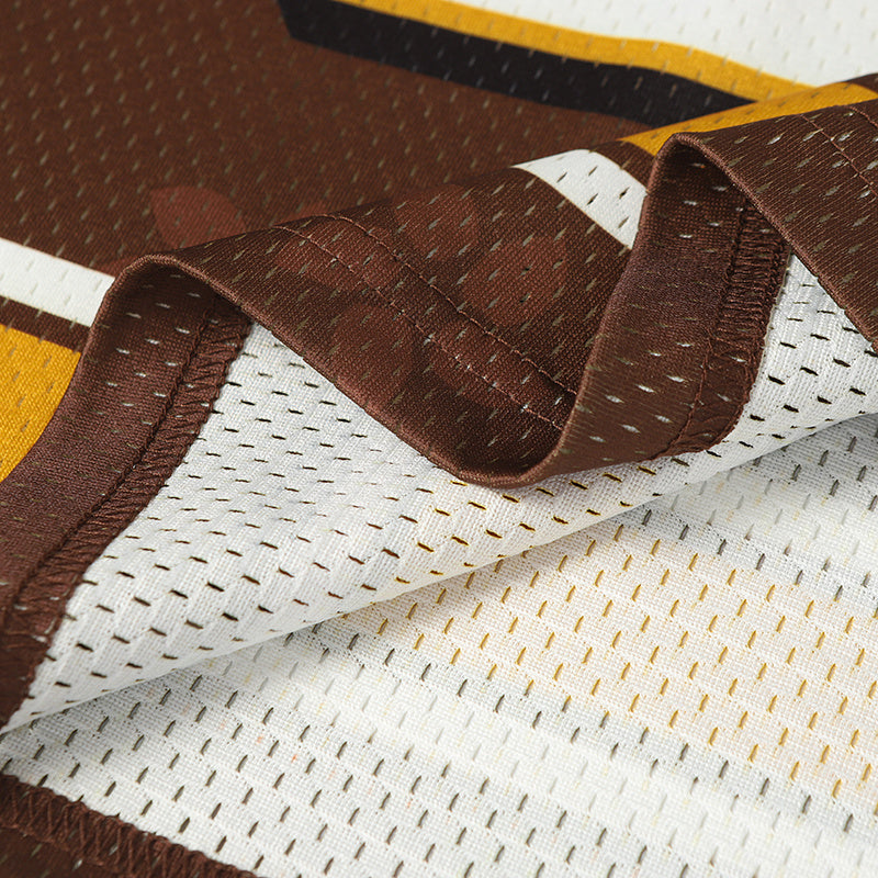 Close-up of a brown and white varsity football jersey fabric with gold accents and stitched mesh texture