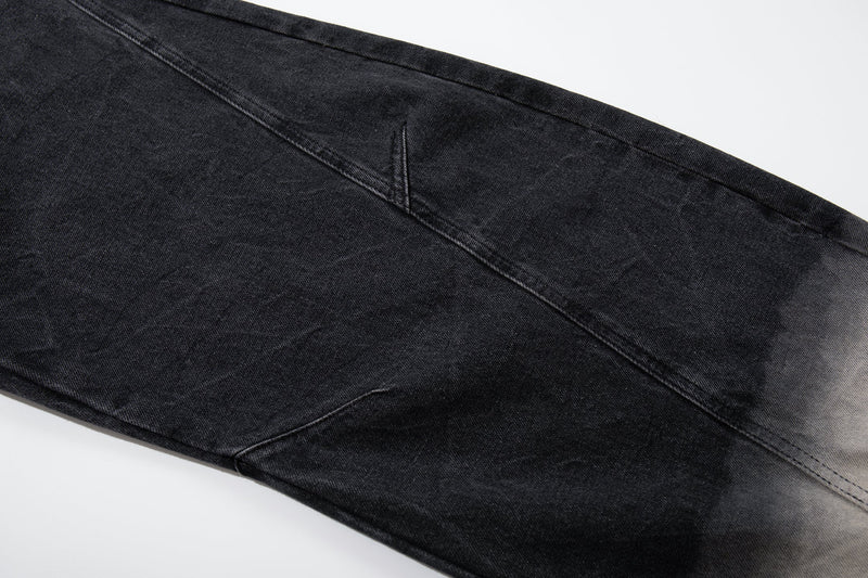 Side view of black denim jeans showing curved panel seam and gradual wash fade