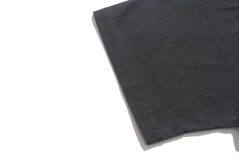 Close-up of a vintage washed black graphic T-shirt sleeve hem with visible stitching and soft faded texture