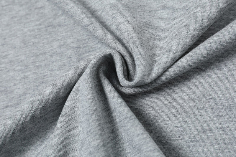 Close-up of heather gray structured T-shirt fabric with a folded panel texture and soft knit detail