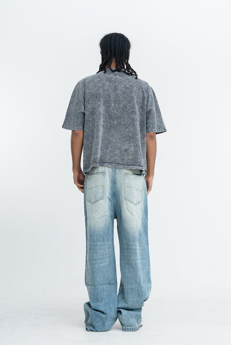 Back view of oversized vintage wash black graphic tee styled with loose light blue jeans on a model