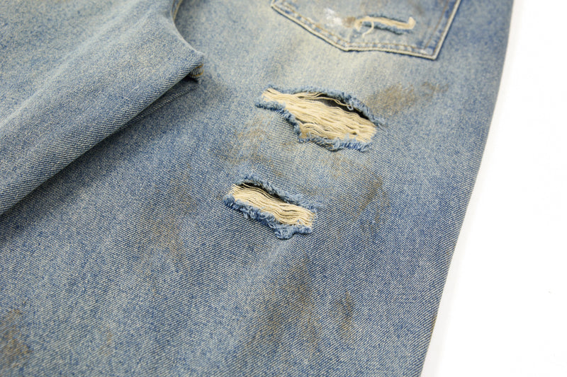 Close-up of distressed front leg with ripped holes and faded wash