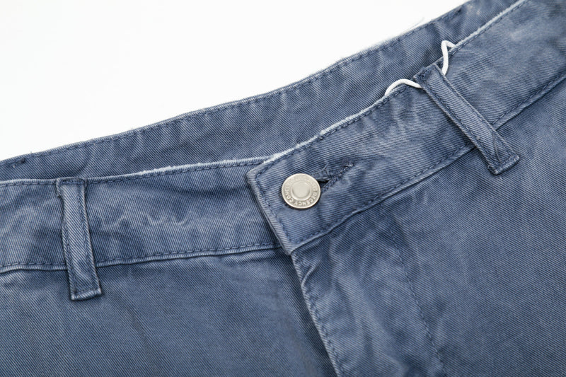 Close-up of front waistband on washed blue cargo pants with button and belt loops