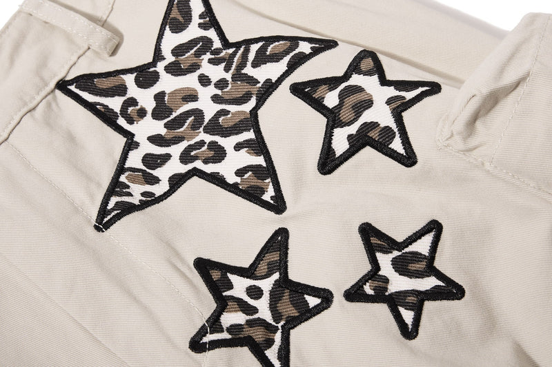 Close-up of beige pants leg with leopard star appliqués and seam lines