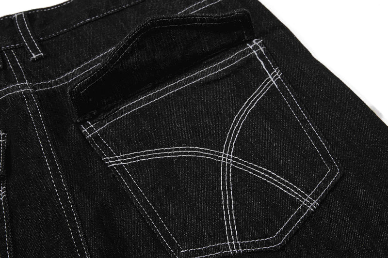 Close-up of back pocket panel on black denim pants with white stitching