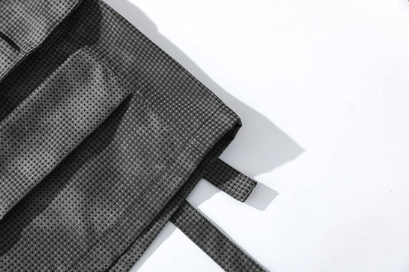 Close-up of black mesh shorts hem with layered fabric strap detail