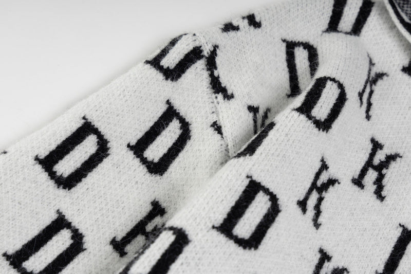 Close-up of white knit fabric with black monogram letters woven into the hoodie