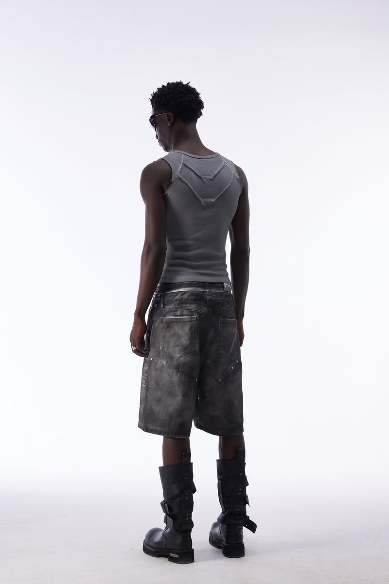 Back view of model wearing gray jorts with back pockets and side spikes