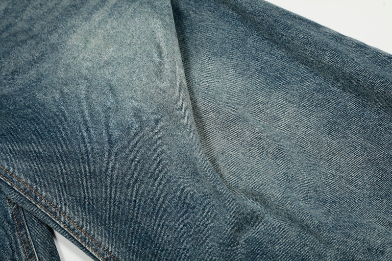 Close-up of blue denim fabric with faded texture and seam line