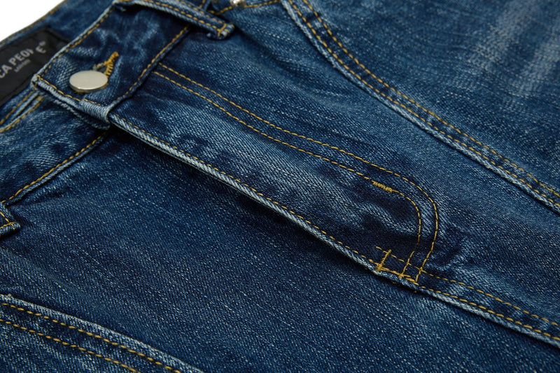 Close-up of blue denim waistband, button closure, and seam stitching