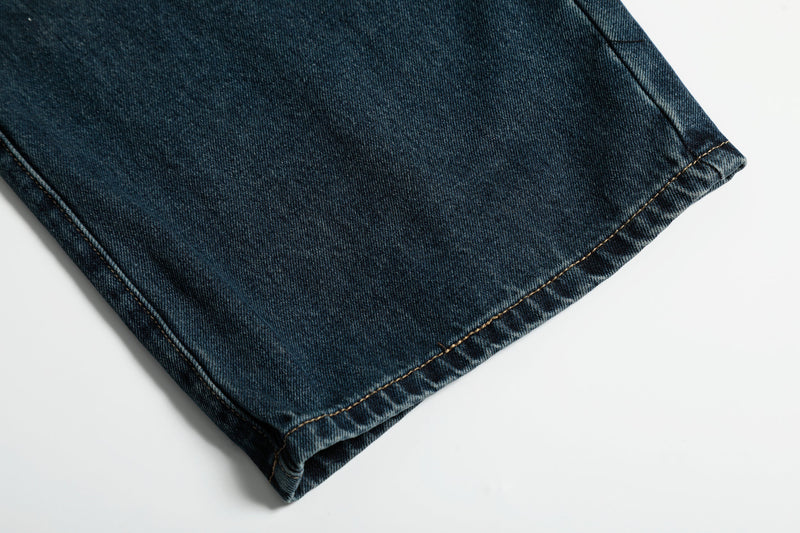 Close-up of hem on dark wash wide-leg jeans with visible topstitching