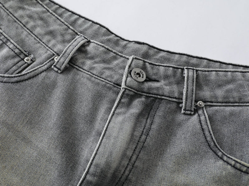 Close-up of grey denim waistband, button fly, belt loops, and topstitched pocket details
