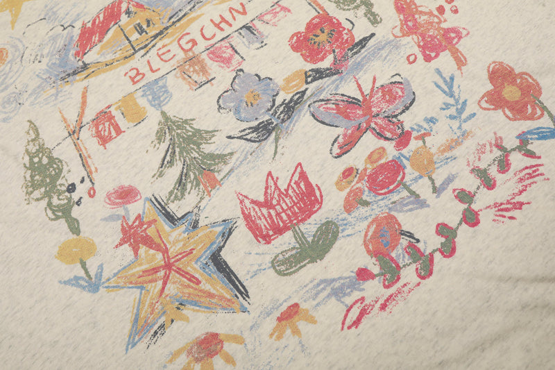 Close-up of colorful front graphic on cream long sleeve tee with flowers and lettering