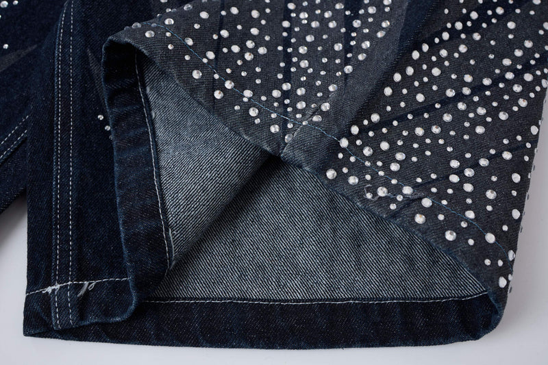 Close-up of dark wash denim shorts hem and side seam with rhinestones
