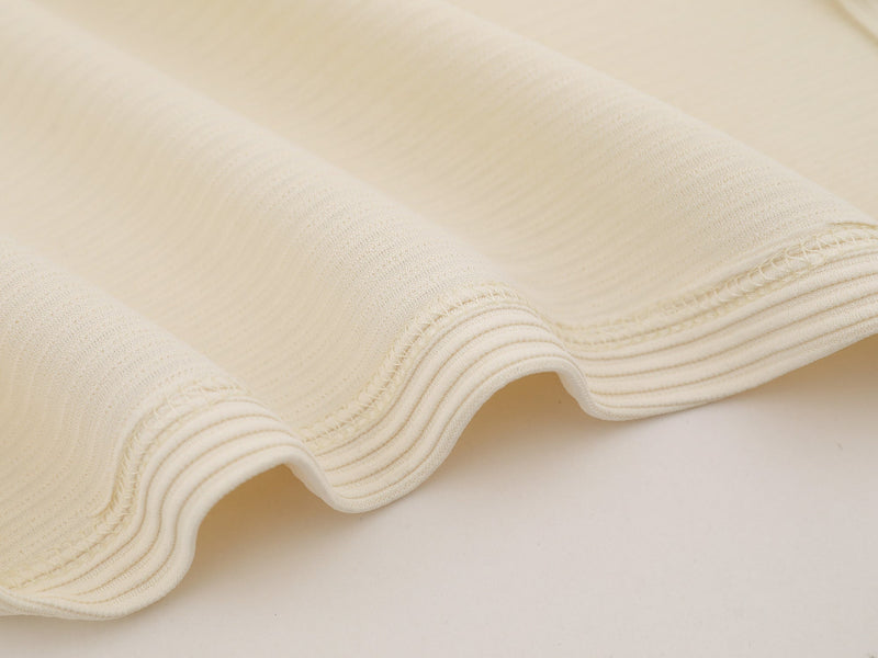Close-up of cream jersey fabric and stitched seam detail