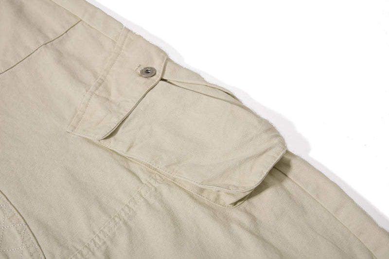 Close-up of beige cargo pant side flap pocket and seam detail