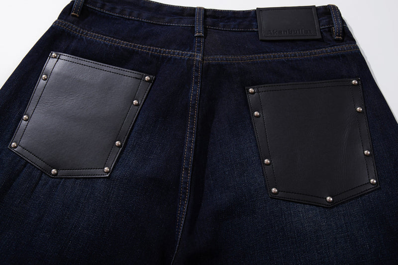 Close-up of two back leather patch pockets on deep indigo wide-leg jeans