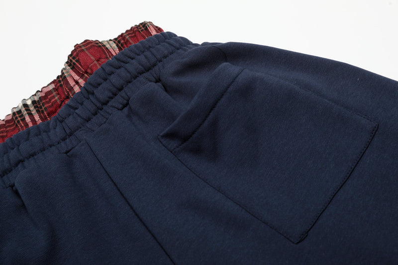Side back pocket close-up on navy shorts with red plaid waistband