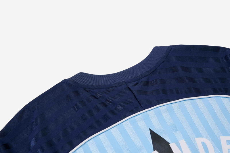 Navy football jersey tee with textured stripe details and light blue chest panel on a white background