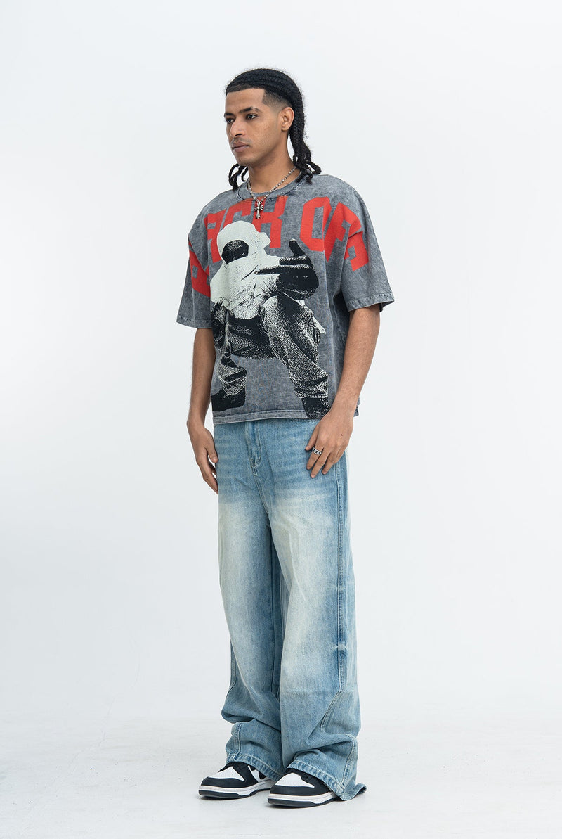 Model wearing a vintage-wash oversized graphic tee with bold red lettering, paired with baggy light-wash jeans and sneakers
