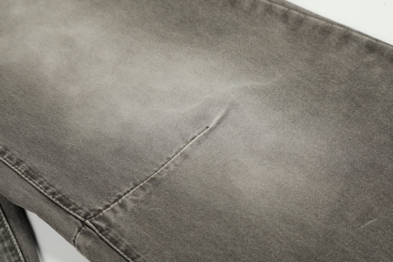 Close-up of grey washed denim leg with faded area and diagonal seam detail